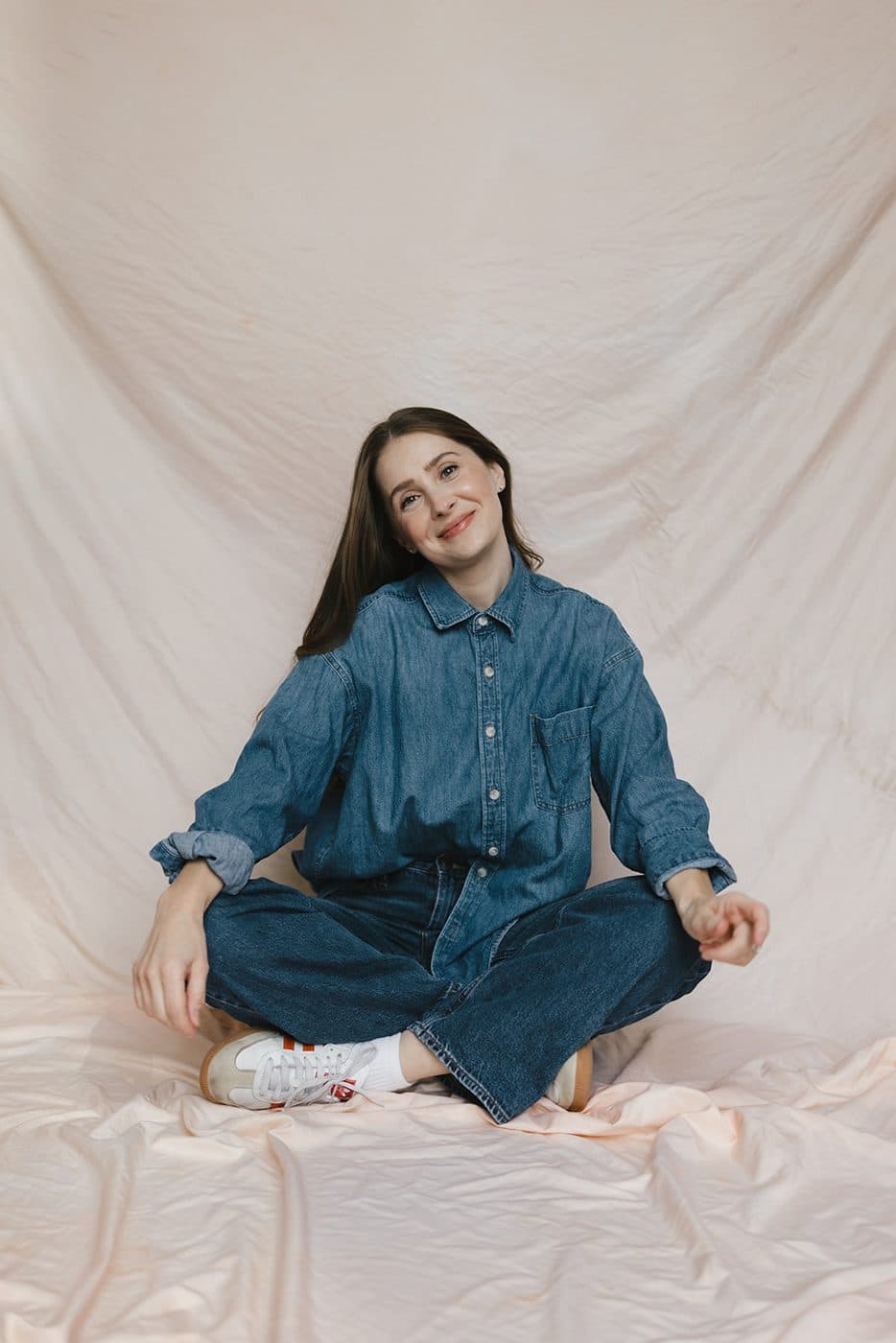 Sara sitting cross-legged in a denim shirt